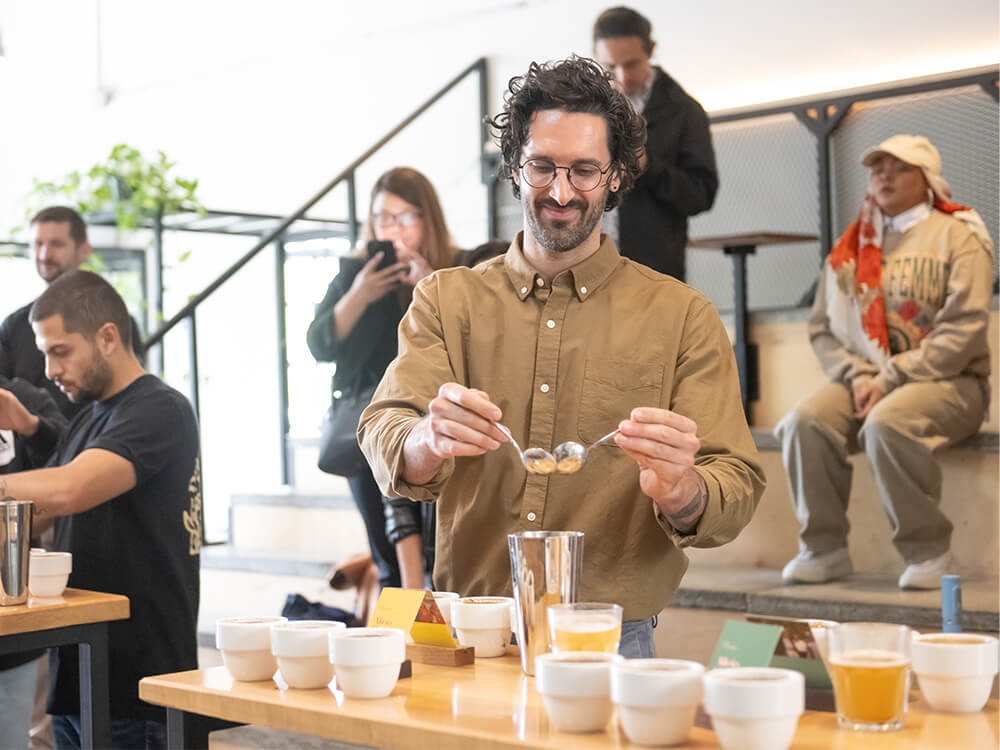 Several people look on while coffee shop employees give a demonstration during a class.
