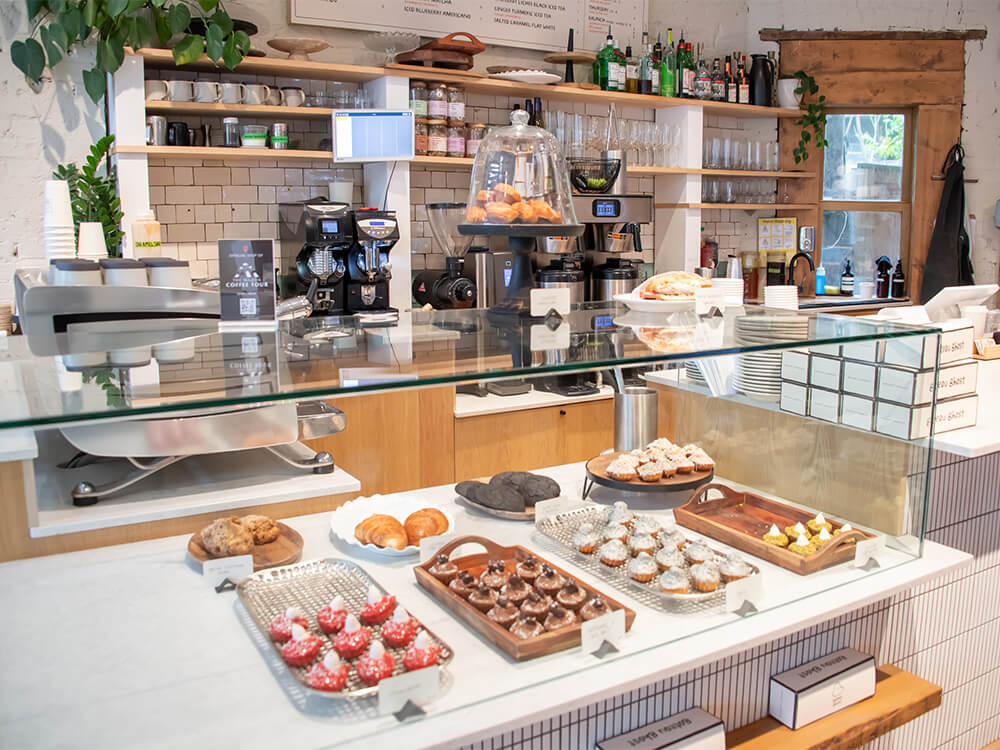 View of a café bakery counter with pastries and other baked goods under the glass.