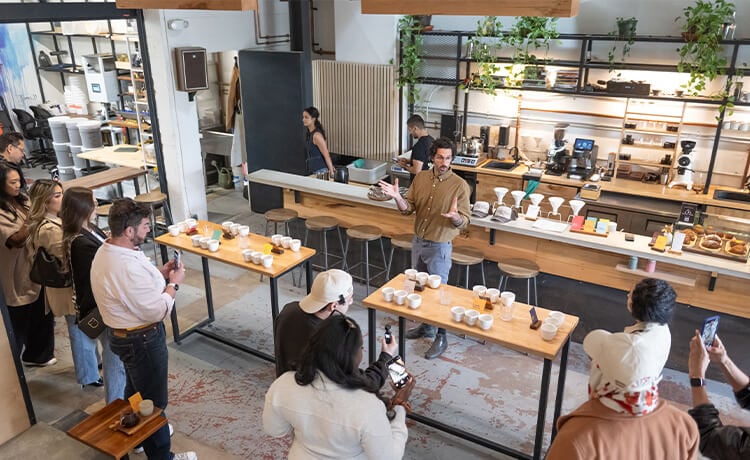 An employee speaks in front of a group of people at a Subtext Coffee Roasters location.