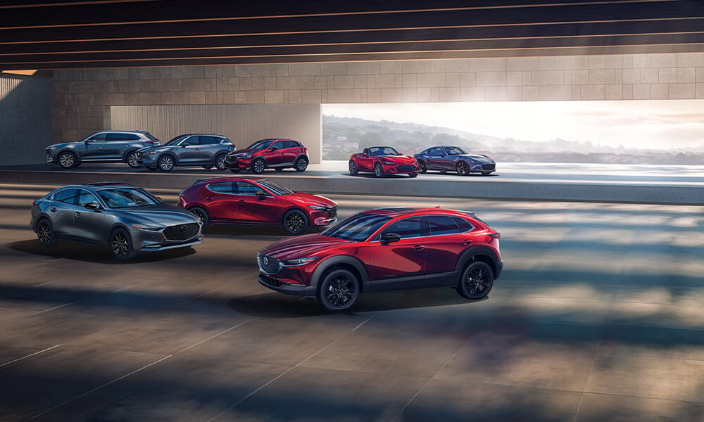 Salle d’exposition présentant un exemplaire de chaque modèle de Mazda en rouge vibrant cristal et bleu éternel mica