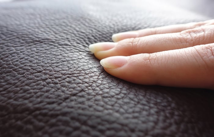 Les doigts d’une femme appuyant sur la surface en similicuir.