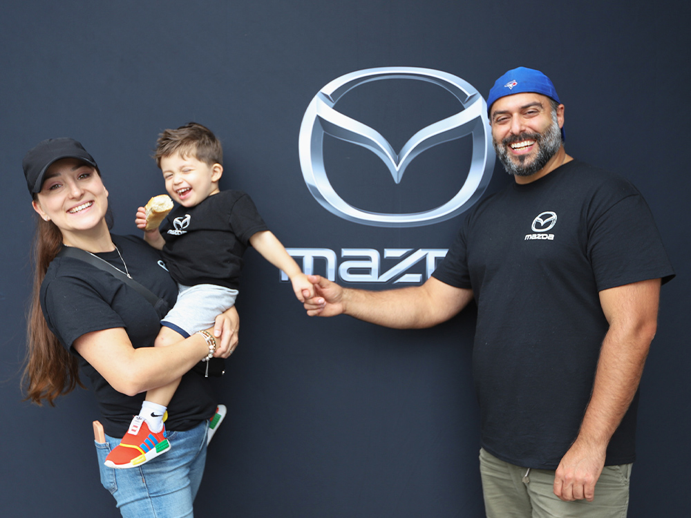 Employees in front of Mazda sign 