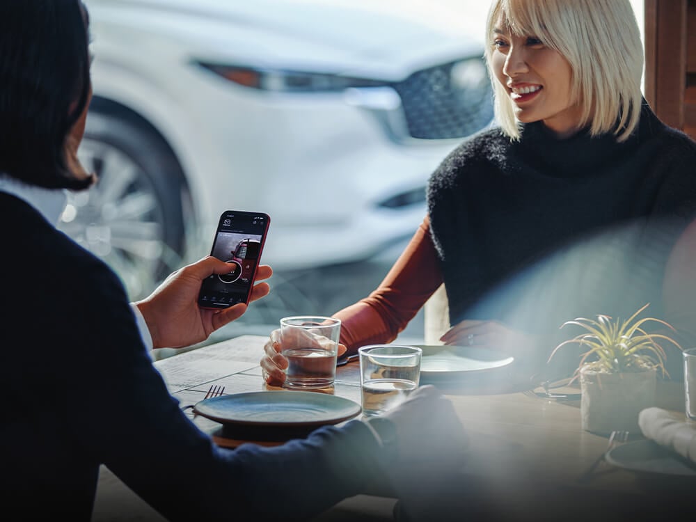 Woman with MyMazda app open at dining table. 
