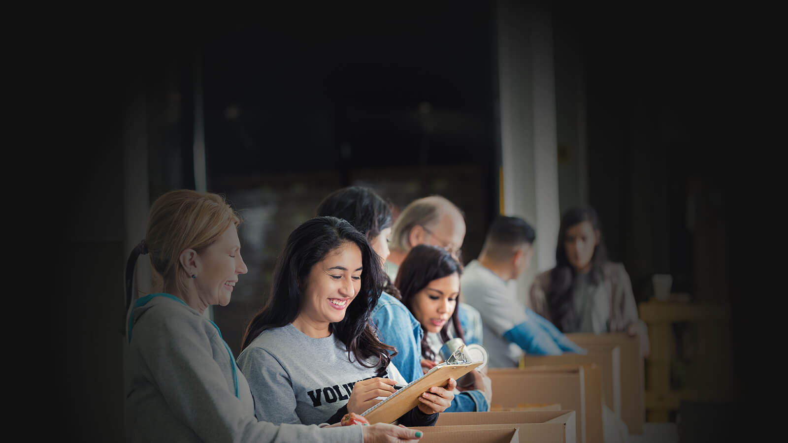 Smiling woman looks at a notepad with other community members.