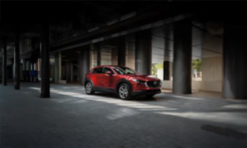 Red Mazda3 Sport parked in front of grey columns 