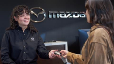 A Mazda Technician checking the oil on a vehicle