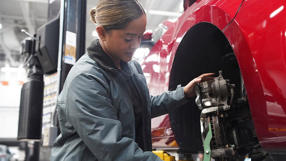 A Mazda technician working on a vehicle's brakes