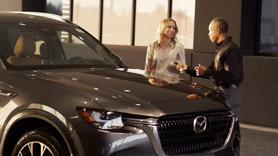 A Mazda technician and a female customer standing next to a CX-90