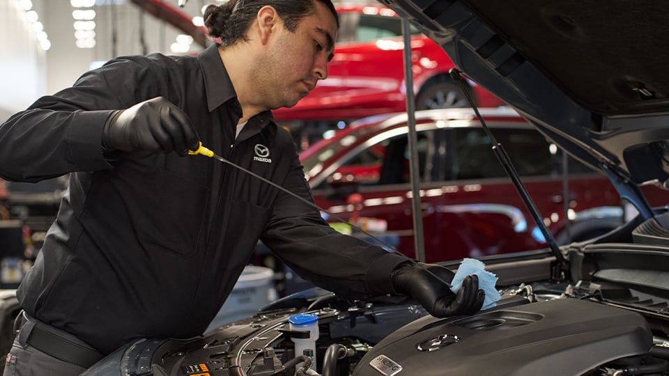 A Mazda Technician checking the oil on a vehicle