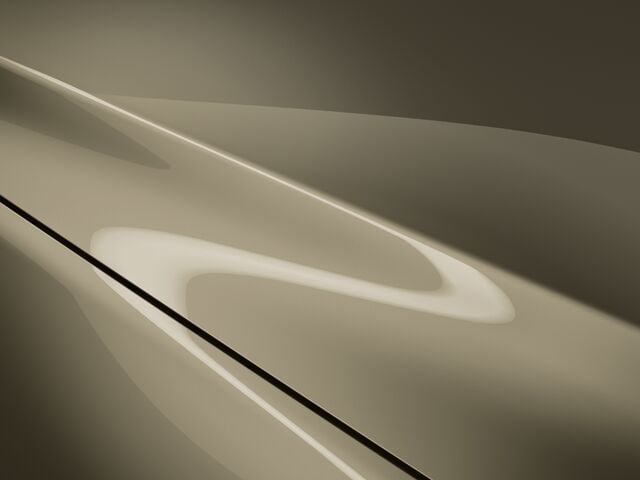 Close up on the hood of a Zircon Sand Metallic CX-5, overhead light reflects accentuating its curves