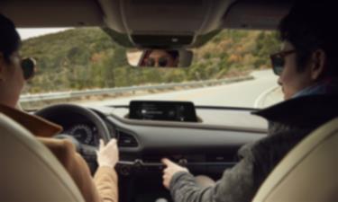 CX-30 driving on mountain road, view from inside, backseat looking forward at the driver and passenger in front seats.