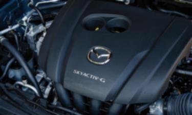 Inside the hood of the CX-30, an engine cover with a Mazda logo badge and Skyactiv G insignia.