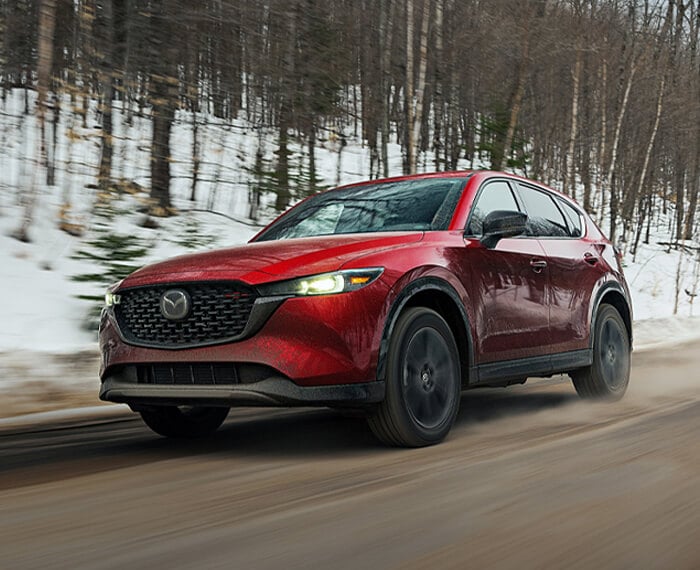 Un CX-5 rouge vibrant cristal métallisé sur une route de campagne hivernale. 