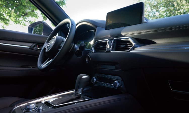 CX-5 steering wheel, dash, display and console seen low view from passenger seat. 