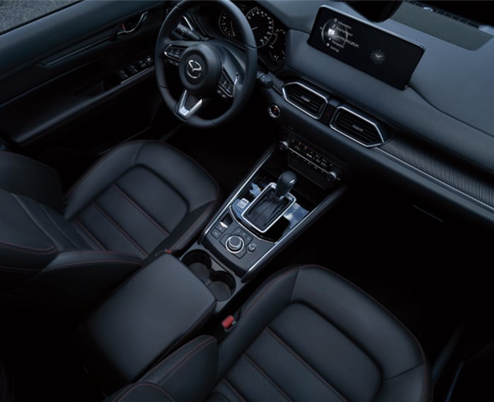 View of Mazda CX-5 front seats from above; black leather with red stitching interior. 