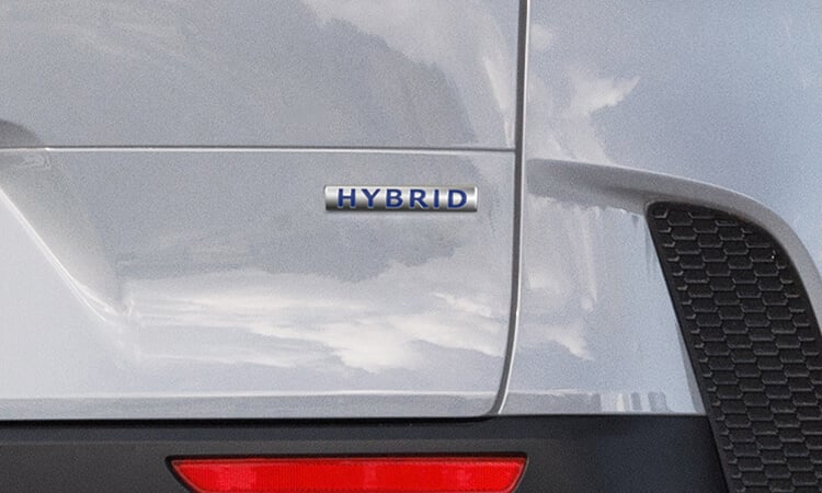 Gros plan de l’emblème « Hybrid » sur le hayon arrière droit d’un Mazda CX-50 hybride vent polaire nacré.