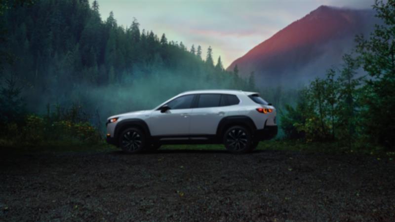 Un CX-50 sable de zircon métallisé circulant dans la forêt, sa calandre face à la caméra.