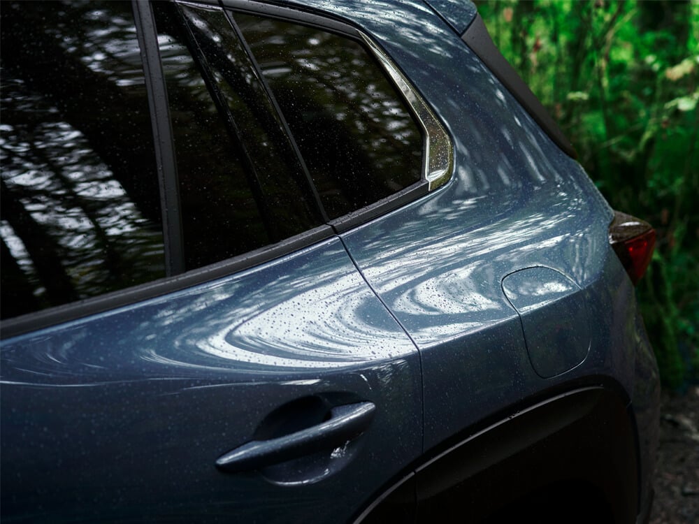 Close up of rain on Ingot Blue Metallic CX-50 rear left side door/handle and rear panel. 