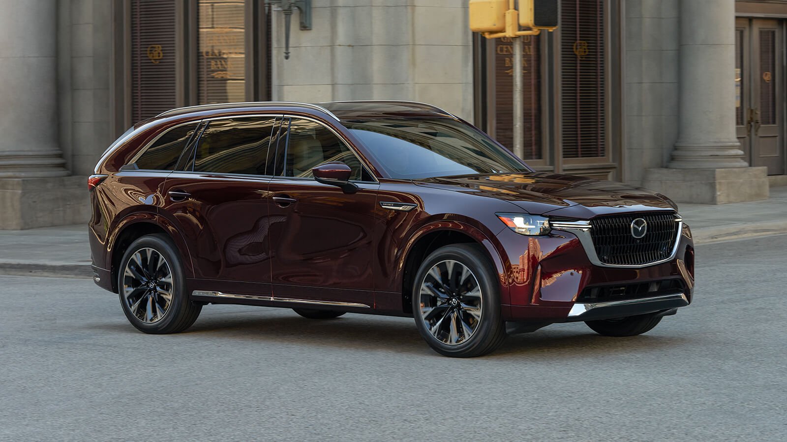 Artisan Red CX-90 is parked 7/8 profile shot in front of historical buildings in business district.