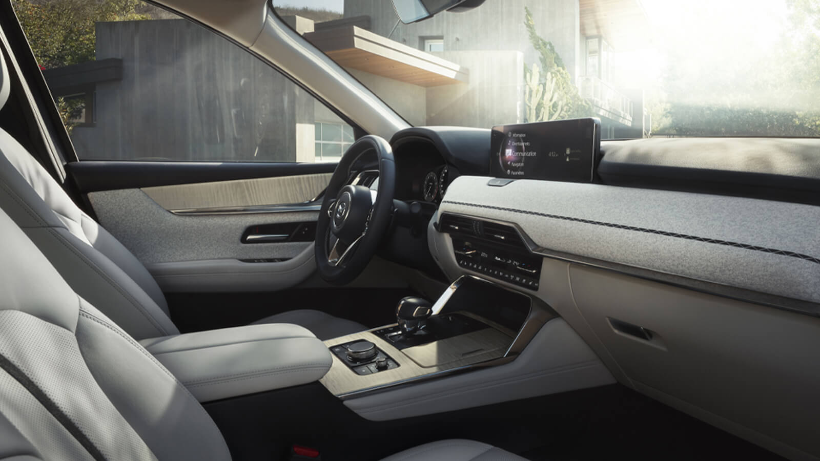 Front passenger view of the CX-90's driver’s seat, steering wheel, interior and dash.