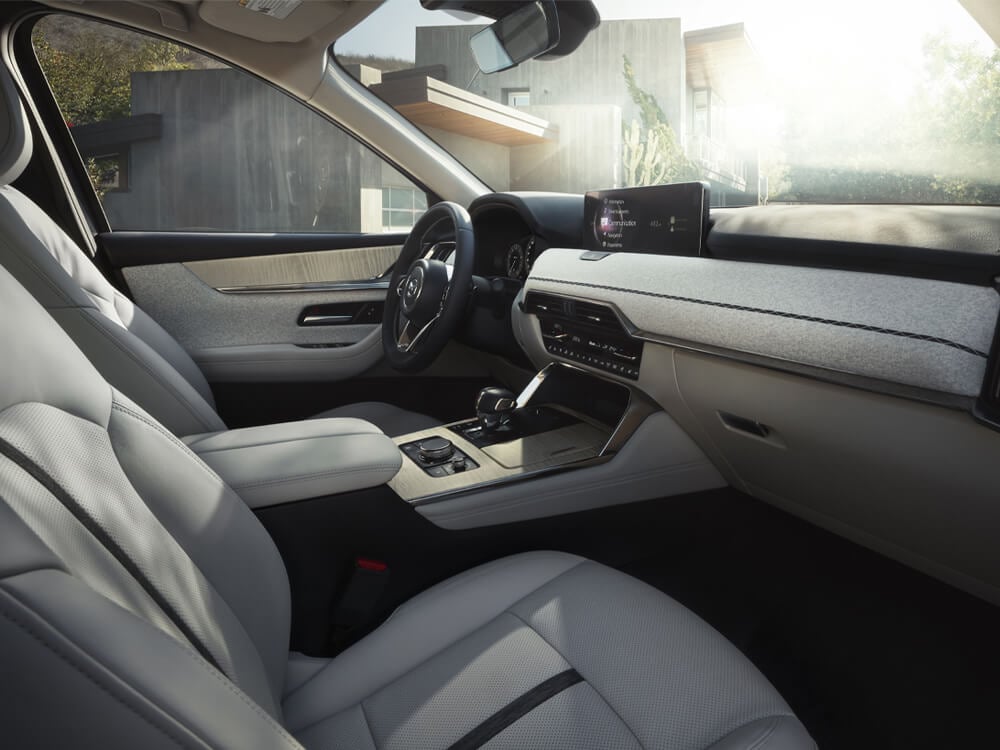 Front passenger view of the CX-90's driver’s seat, steering wheel, interior and dash.