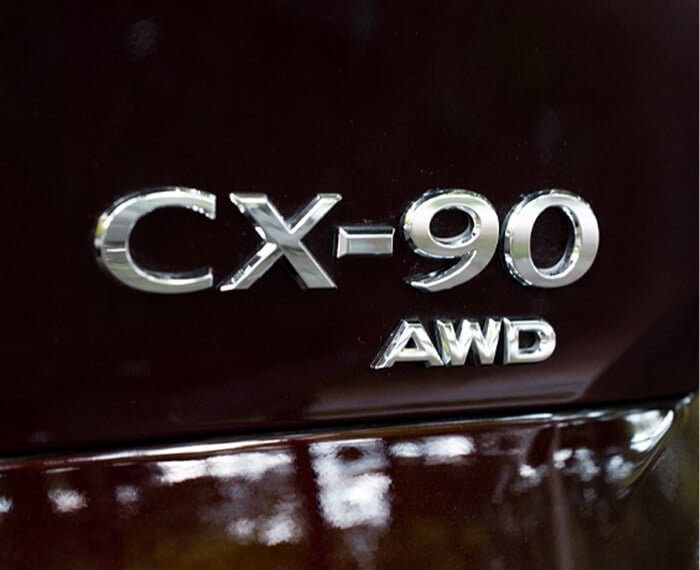 Close-up of CX-90 AWD vehicle nameplate badge.