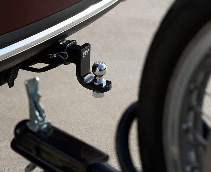 Close up of tow hitch and ball, out of focus in foreground is a bicycle trailer.