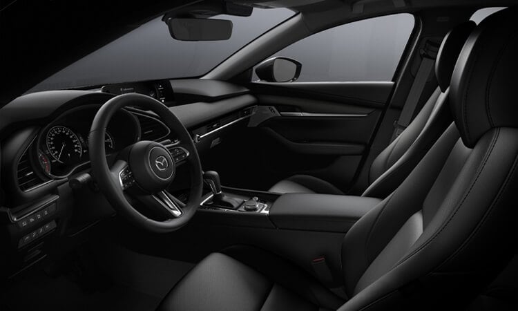 De la fenêtre côté conducteur, on aperçoit les confortables sièges avant d’une berline Mazda3. 