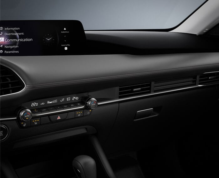 Gros plan de l’intérieur d’une berline Mazda3, du point de vue du conducteur; on voit la planche de bord du centre vers la droite. 
