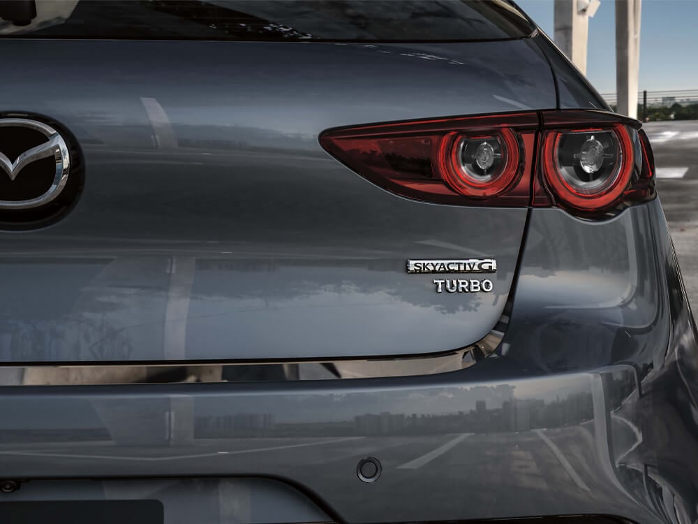 Close-up of Skyactiv-G TURBO badge and Mazda logo on rear hatch door.