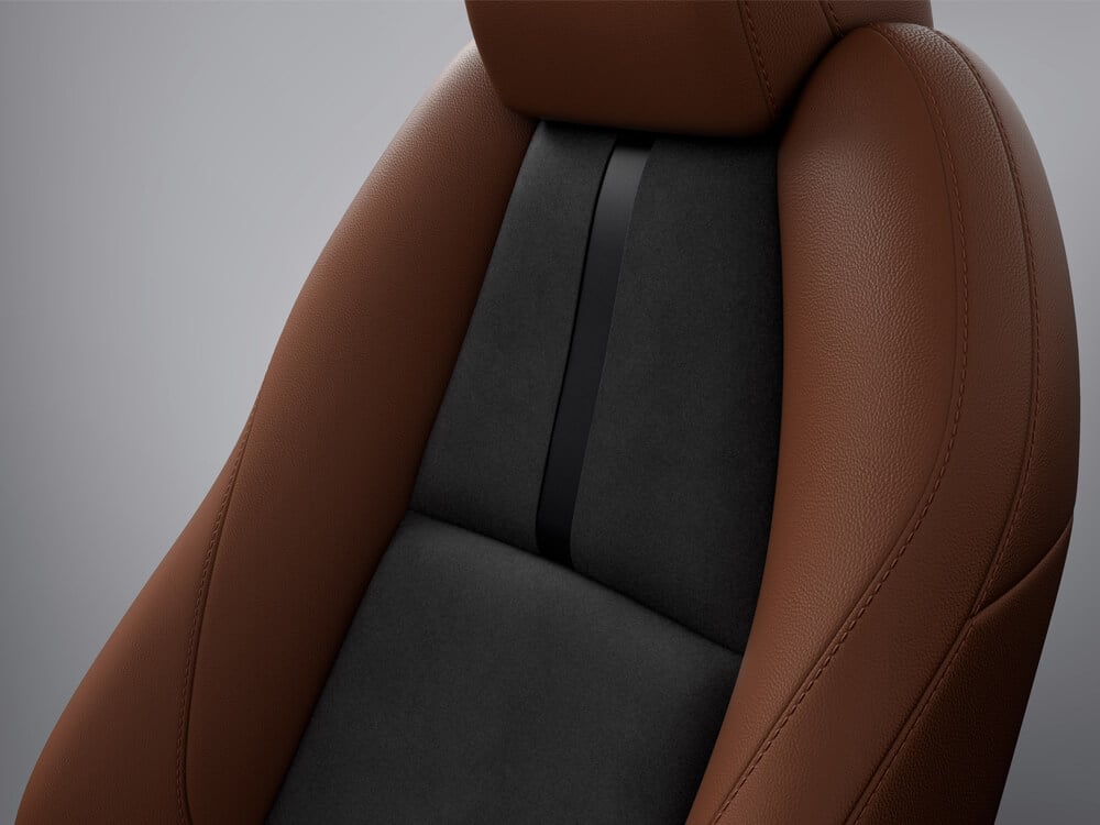 In studio, not situ, closeup of materials and detail on Terracotta/Black Leatherette seat of Mazda3 Sport Suna Edition.