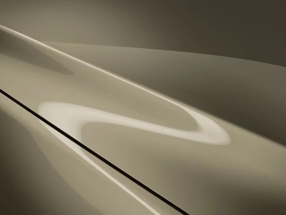 Extreme close-up of hood of Mazda3 Sport Suna, light and Zircon Sand Metallic paint shows off the contours of the metal.