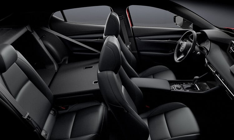 Vue en plongée côté passager de l’habitacle complet d’une Mazda3 Sport; l’un des sièges arrière est abaissé, montrant l’accès à l’espace de chargement.