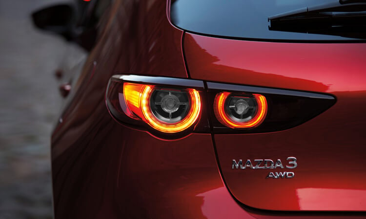 Gros plan sur l’emblème AWD et les feux arrière d’une Mazda3. 