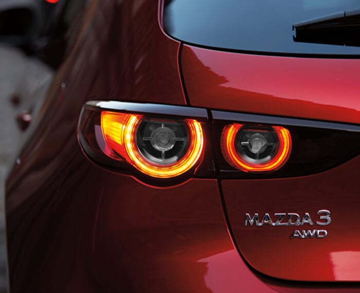 Gros plan sur l’emblème AWD et les feux arrière d’une Mazda3. 