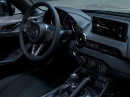 Close-up view of the MX-5 RF interior from the passenger side with steering wheel, dashboard and cabin controls visible. 