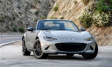 Une MX-5 ST argent roule sur une route traversant les montagnes.