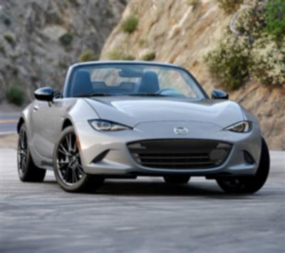 Une MX-5 ST argent roule sur une route traversant les montagnes.