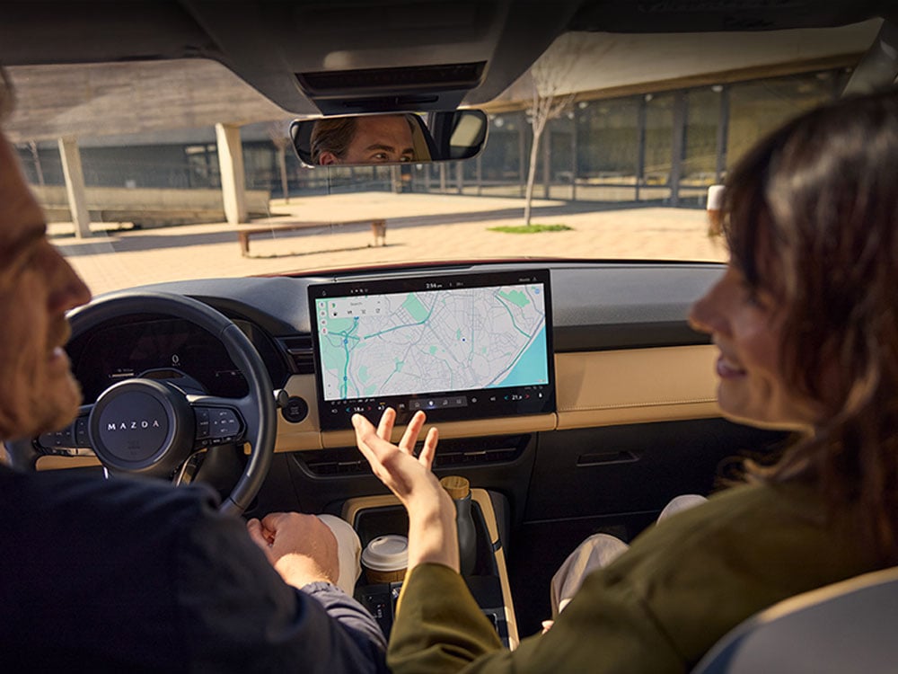 View from behind of two people in the front seats, with the centre display showing Google Maps navigation