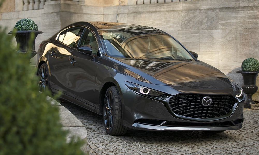 Side profile of a man entering a Machine Grey Metallic Mazda3.