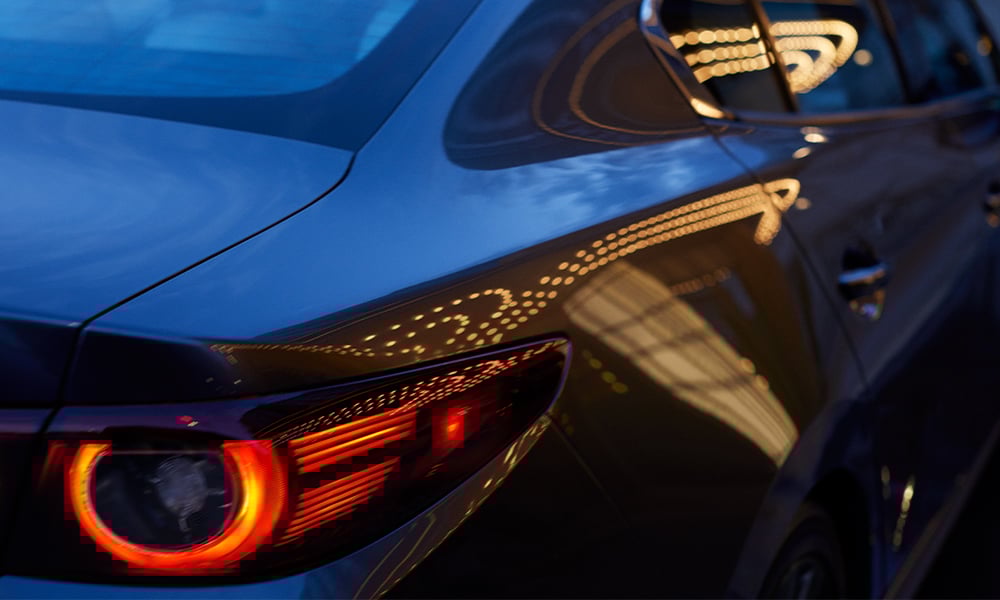 View through the panoramic moonroof of a Mazda3, looking down at a hand resting on the centre control knob.